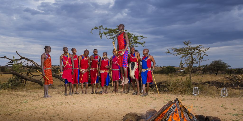 Maasai warriors performing traditional dance near campfire, Kenyan cultural experience